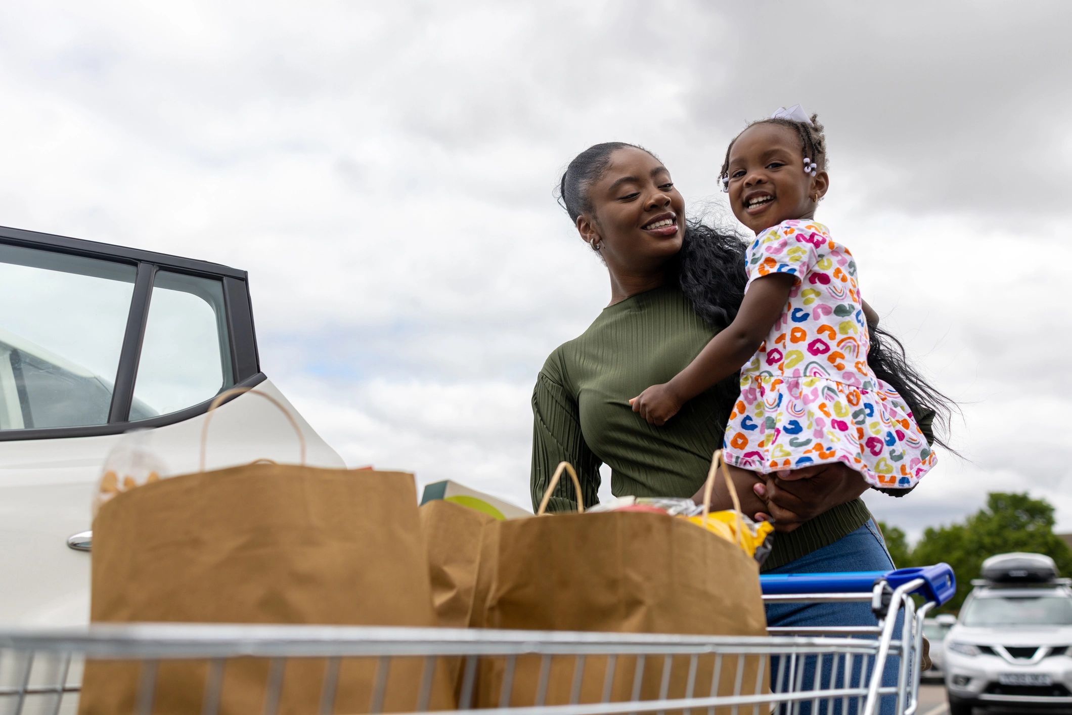 Family unloading supermarket groceries into a car