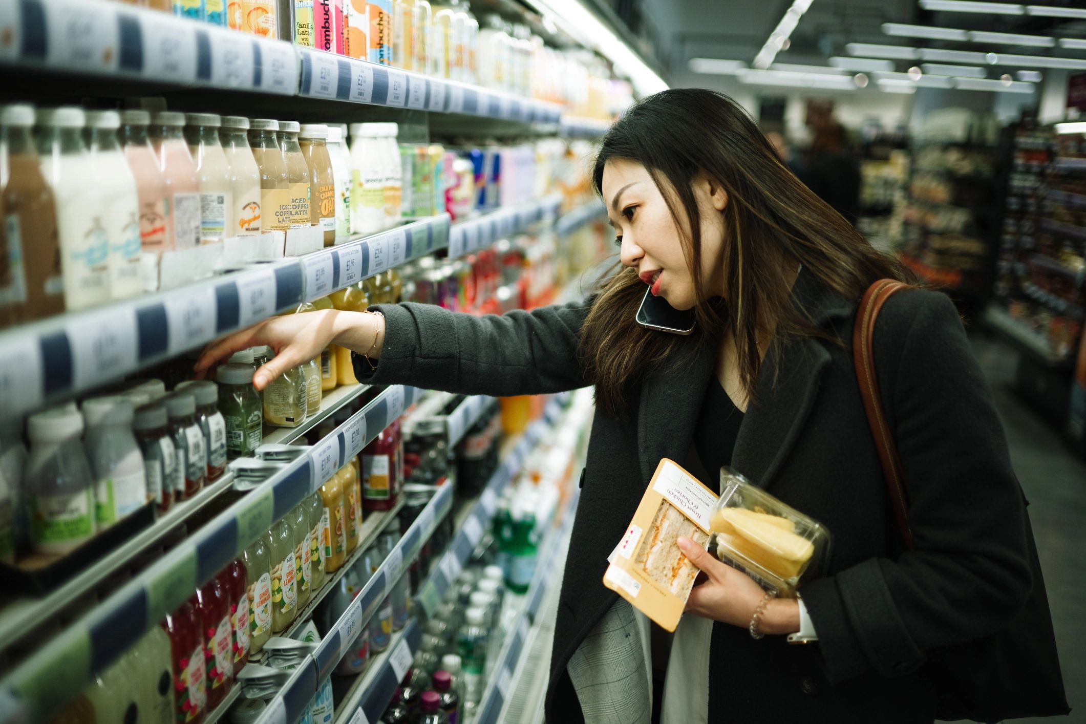 Shopper using a phone while browsing a supermarket aisle
